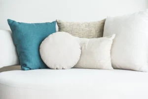 Cojines de diferentes formas y colores sobre un sofá claro, ideal para ilustrar cómo elegir cojines para el sofá y combinarlos